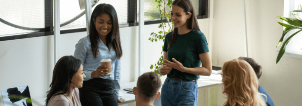 Young adult employees talking and laughing in a conference room. 